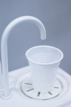 Dentist's water cup and tap pip  filler in dental clinic in artistic blue purple white tones.
