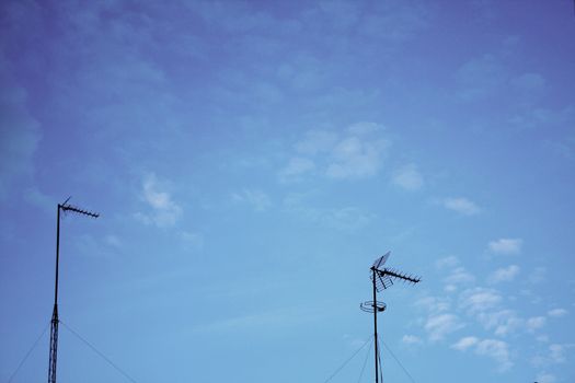 TV arial television antenna tied with metal cables onto roof of a building and blue sky in Madrid Spain. 