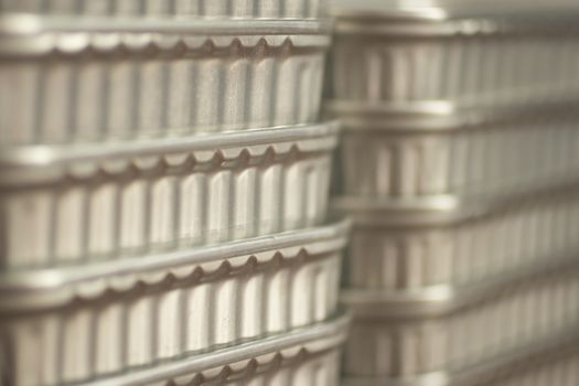 Color photo of grey metal aluminium cans of tinned sardine fish tins stacked up with shallow depth of focus. 