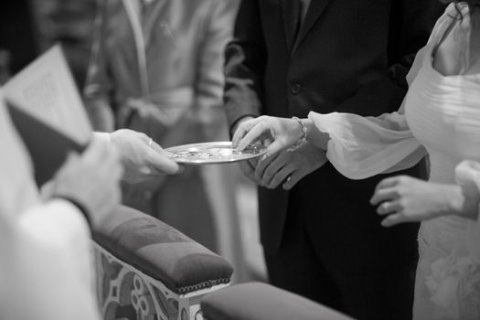 Bride in white dress and bridegroom in catholic wedding religious marriage church ceremony exchanging Arras wedding silver coins