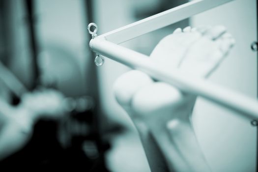 Feet of a young woman realising an exercise of pilates on a pilates machine bar in a healthclub gym specialized training room. Black and white monochrome photo in blue tone. 