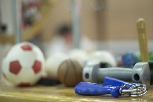 Hand exerciser, mini football, mini basketball, dumbell weight and other physiotherapy rehabilitation treatment equipment for pateint recovery from orthopedic surgery in a hospital clinic physiotherapy room on a wooden table.