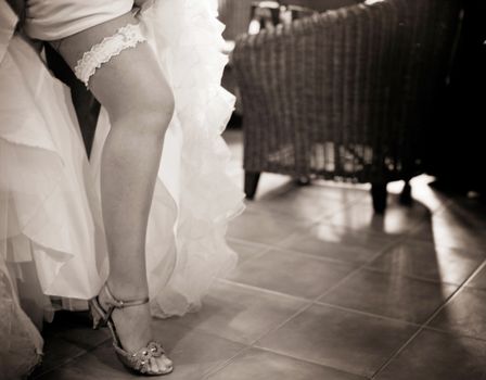 Young exhibitionist bride in wedding and garter belt stockings lingerie showing legs in public in wedding reception party bar.
