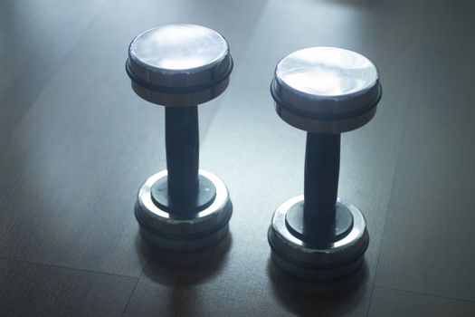 Dumbbell gym metal weights on wooden floor in exercise room in gym health club.