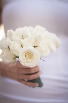 Bride in white wedding dress holding bouquet of roses flowers close-up photo. 