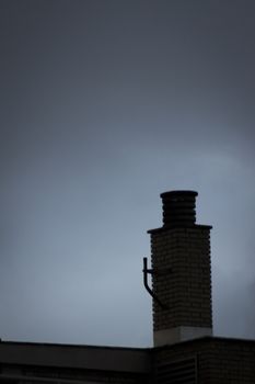 Brick chimney pot on roof of building and blue dusk evening sky in Madrid Spain. 