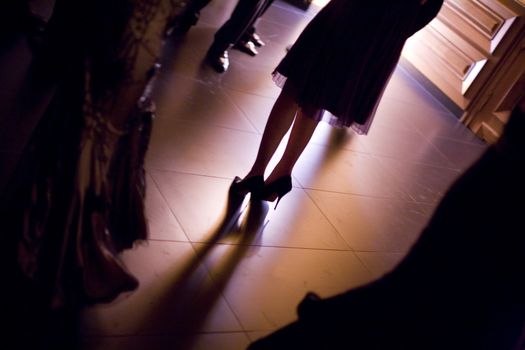 Feet of young woman wedding guest in high heel shoes and cocktail party dress in wedding reception. 