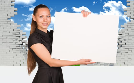 Beautiful businesswoman holding blank paper sheet. Dilapidated brick wall, sky and clouds as backdrop. Business concept