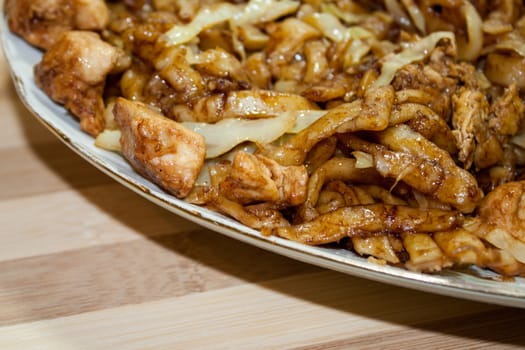 Fried spaghetti with chicken on the wooden board.