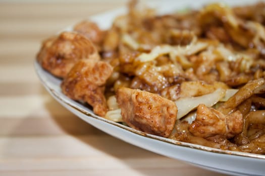 Fried spaghetti with chicken on the wooden board.