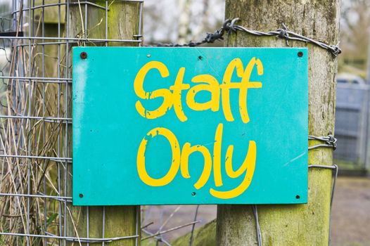 Green staff only notice on a wooden fence post