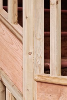 Close up of part of a wooden stair case with bannisters