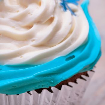 Close up of part of a cupcake with blue and cream icing