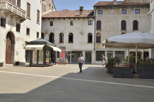 A woman walking in a square of the historical part of the town of Bassano del Grappa, Italy