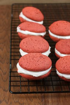 Red velvet whoopie pie with a peppermint cream cheese filling on a metal cooling rack.