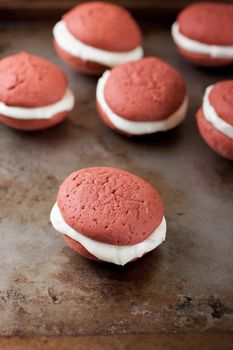 A red velvet whoopie pie with a peppermint cream cheese filling on a metal surface.