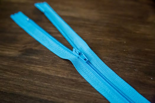 Blue clothing zipper on dark wood background