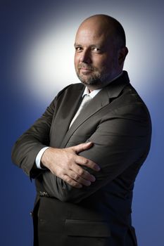 Serious businessman in dark suit and tie in front of blue background