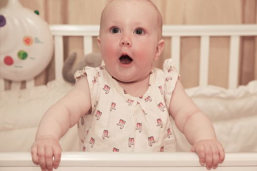 Little girl in a baby cot