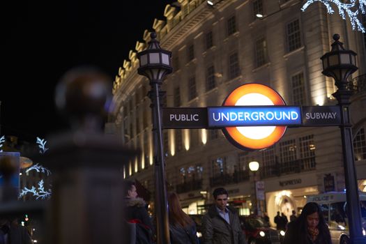 LONDON, UK - DECEMBER 19: Detail of Piccadilly underground station entrance at night, with busy street in the background. December 19, 2014 in London.