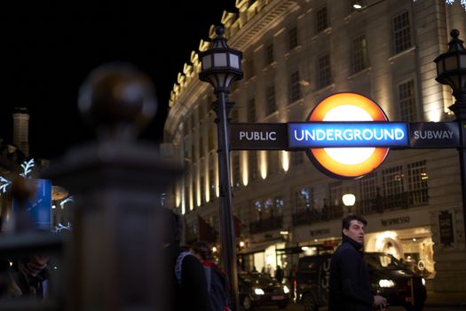 LONDON, UK - DECEMBER 19: Detail of Piccadilly underground station entrance at night, with busy street in the background. December 19, 2014 in London.