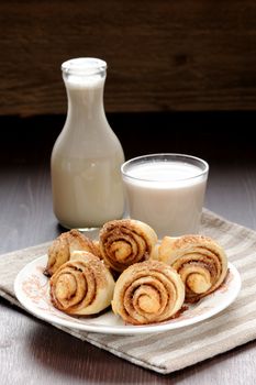 Cinnamon rolls with glass and bottle of milk on wood table