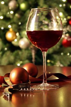 Glass of red wine on table with holiday tree in background