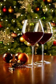 Glasses of red wine on table with Christmas tree in background 