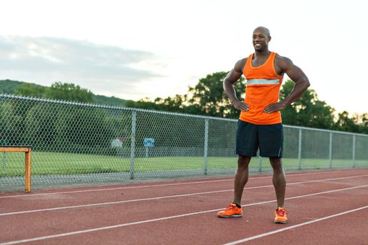 African American man in his 30s posing at a sports track outdoors.