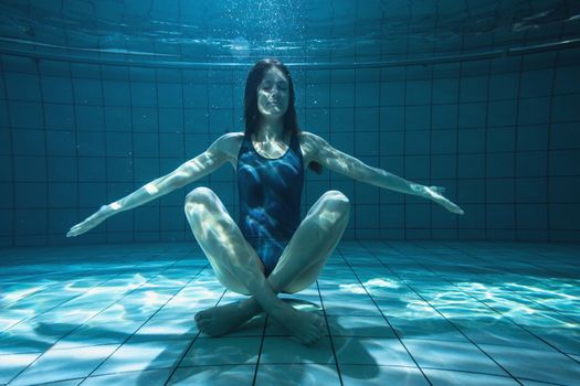 Athletic swimmer smiling at camera underwater in the swimming pool at the leisure centre