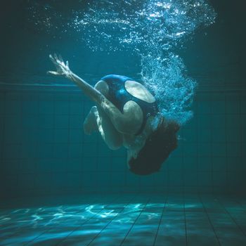 Athletic swimmer doing a somersault underwater in the swimming pool at the leisure centre