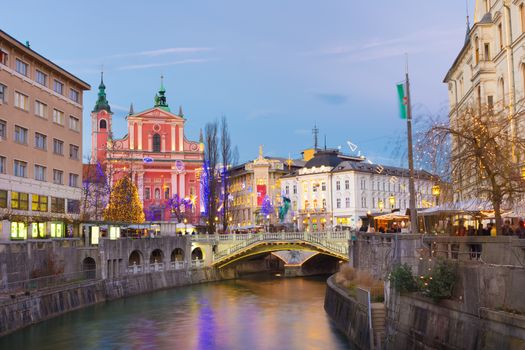 View of Ljubljanica river and Tromostovje in old city center decorated with Christmas lights at dusk. Ljubljana, Slovenia, Europe. 