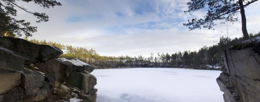 Panorama of an abandoned stone pit in winter 