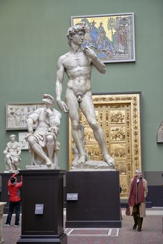LONDON, UK - DECEMBER 20: Plaster cast copy of Michelangelo's David at the Victoria and Albert museum, with visitors walking past. December 20, 2014 in London.