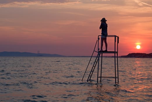 Photo shows a sunset above the beach and sea.