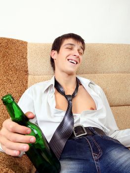 Drunken Young Man with Bottle of the Beer on the Sofa at the Home