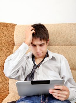 Troubled Teenager with Tablet Computer on the Sofa at the Home