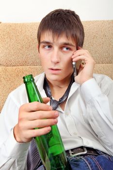 Teenager with Bottle of the Beer and Cellphone on the Sofa at the Home