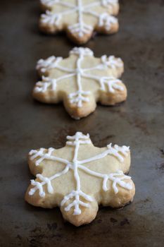Snowflake shaped shortbreat cookies with chocolate dipped bottoms and icing on top.