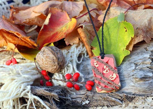 Ethnic handmade magic red clay amulet on autumn-style background