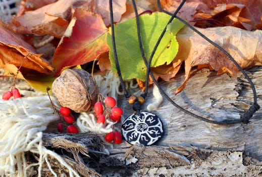 Ethnic handmade magic clay b&w amulet on autumn-style background