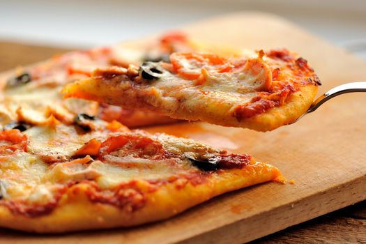 Pizza with olives and salmon and fresh greens on wooden board