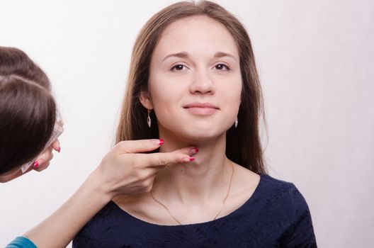 Makeup artist applies foundation of a beautiful young girl in the makeup