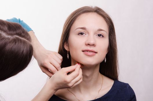 Makeup artist applies foundation of a beautiful young girl in the makeup