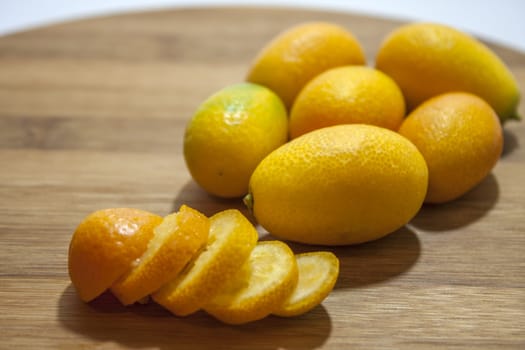 Kumquat slices on the wooden board on the white background.