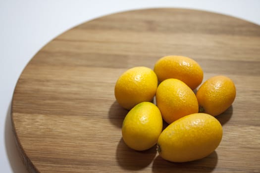 Fresh fruit kumquat on the kitchen wooden board.