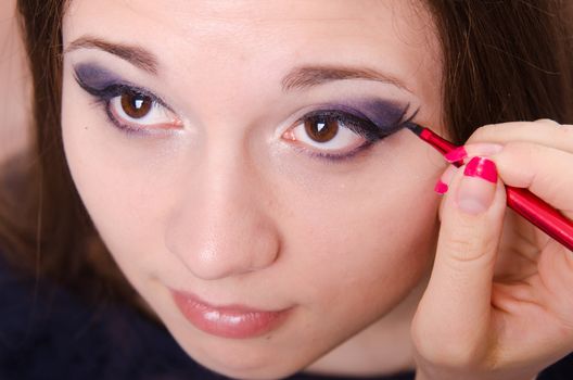 Makeup artist draws arrows beautiful young girl in the makeup