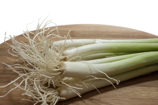 Young onions on the kitchen wooden board.