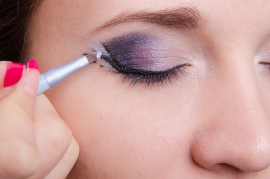 Makeup artist draws arrows beautiful young girl in the makeup