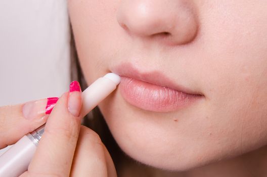 Makeup artist paints her lips a beautiful young girl in the makeup